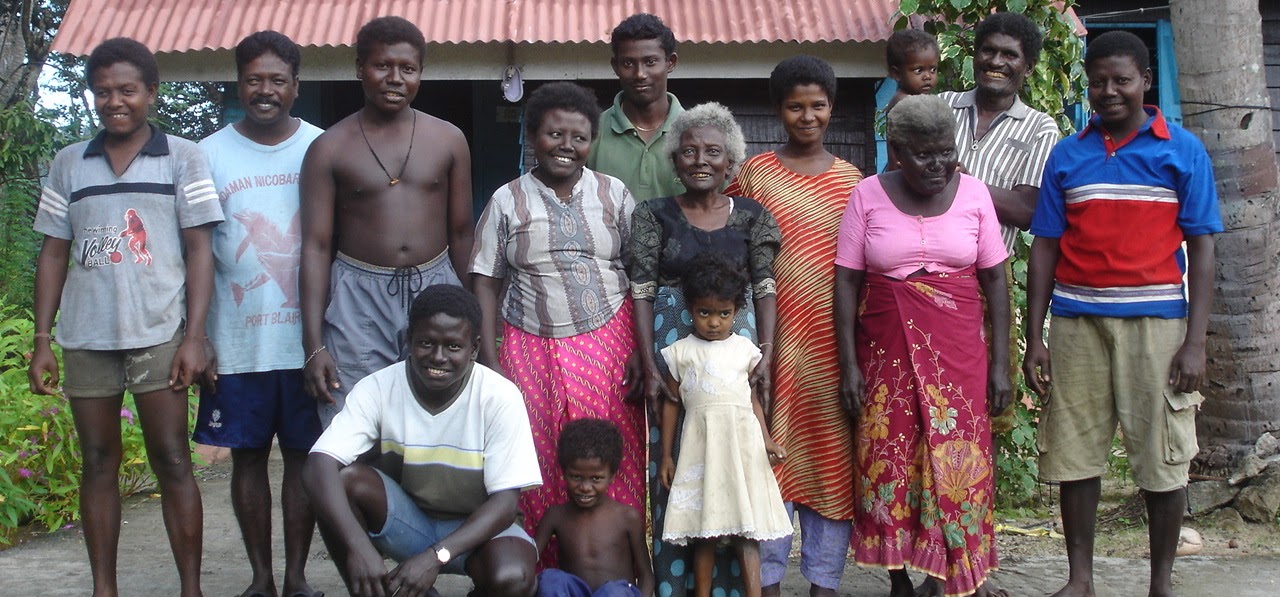 Members of the Great Andamanese community standing together outside a home in the Andaman Islands